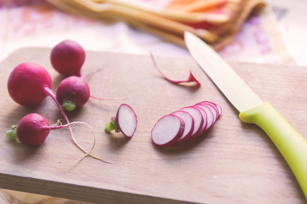 Freshly sliced radishes on a cutting board with a knife, perfect for healthy recipes.